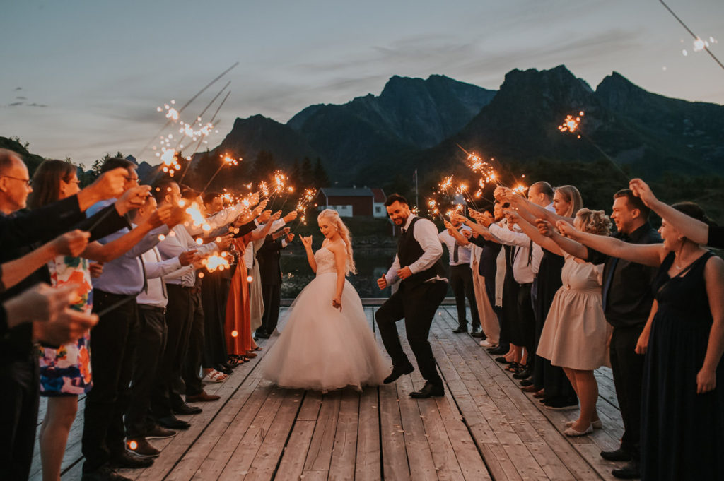 Sparkler exit on a wedding day in Lofoten Norway. Bride and groom are dancing trherugh the exit and laughing