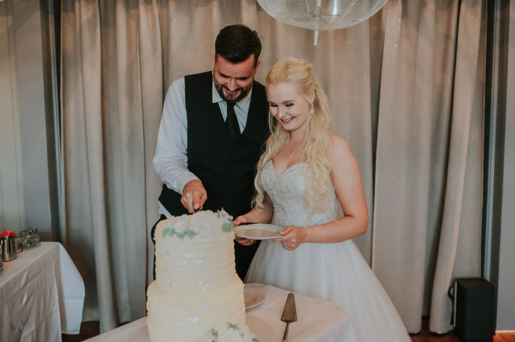 Bride and groom cutting the cake at a wedding party in a Nyvågar rorbu hotel in Lofoten. Guests are having good time and laughing all the time