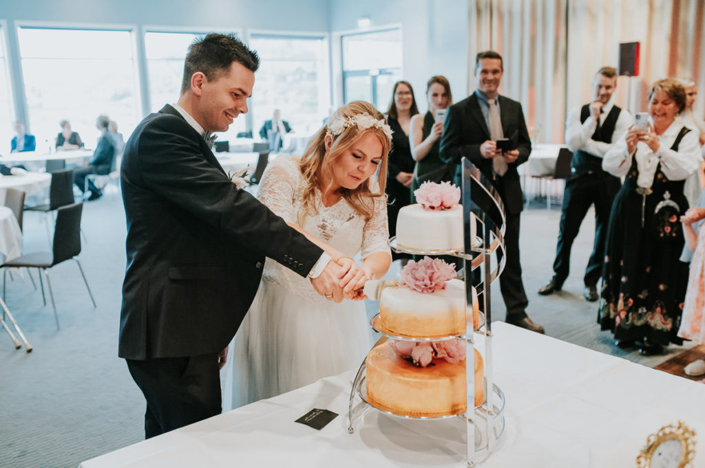 Bride and groom cutting a three layers cake decorated with peonies 