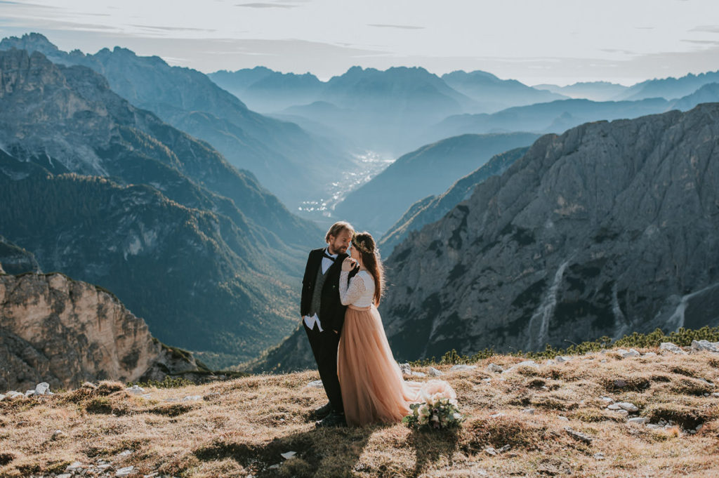 Bride and groom standing on a cliff in mountains of Northern Italy - captured by Dolomites wedding photographer TS Foto Design 