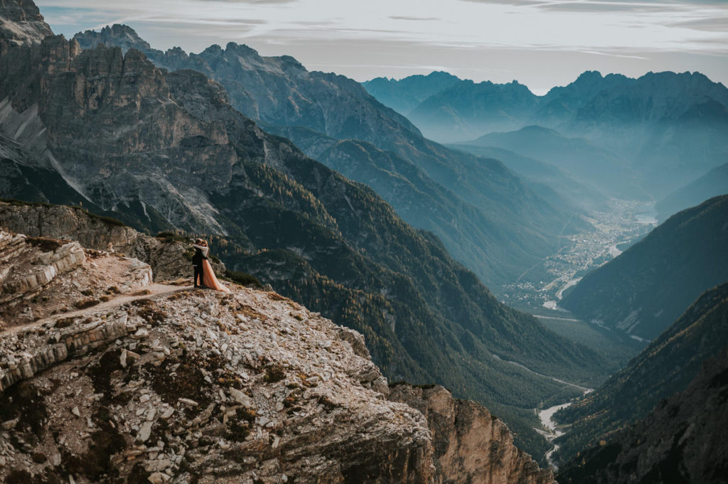 Bride and groom standing on a cliff in mountains of Northern Italy - captured by Dolomites elopement photographer TS Foto Design 