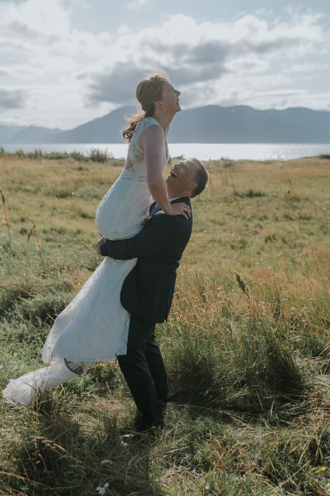Groom lifted his bride and she is laughing while he swirls her
