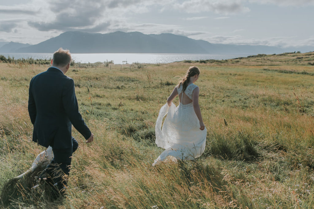 Bride and groom walking in a grass field