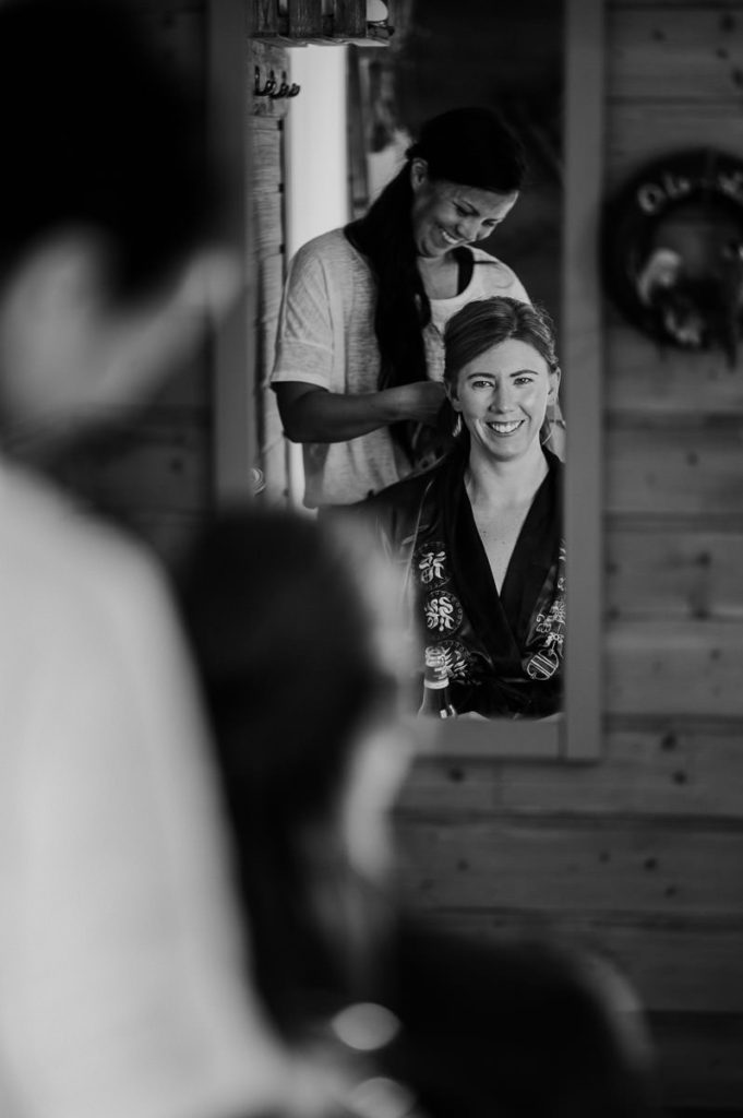 Black and white portrait of a bride looking in a mirror and smiling
