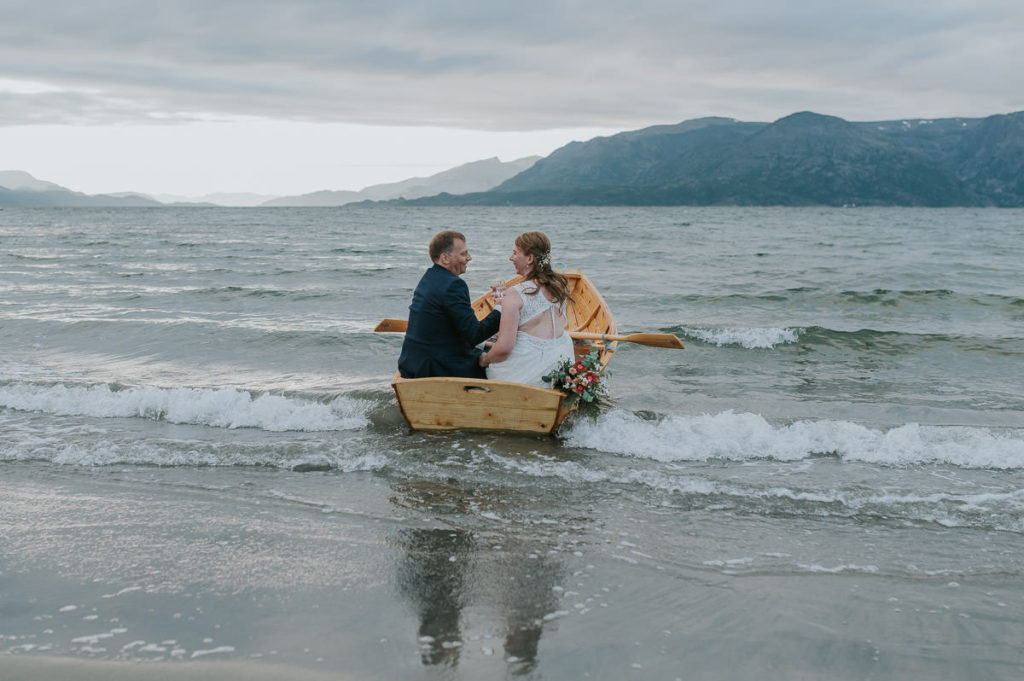 Bride and groom rowing boat on their wedding day in the sunset in  Storekorsnes Alta Norway