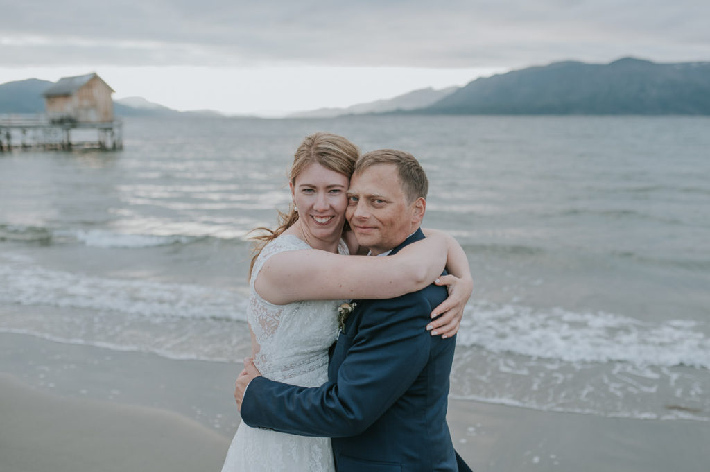Bride and groom on a beach with a mountain view in Norway