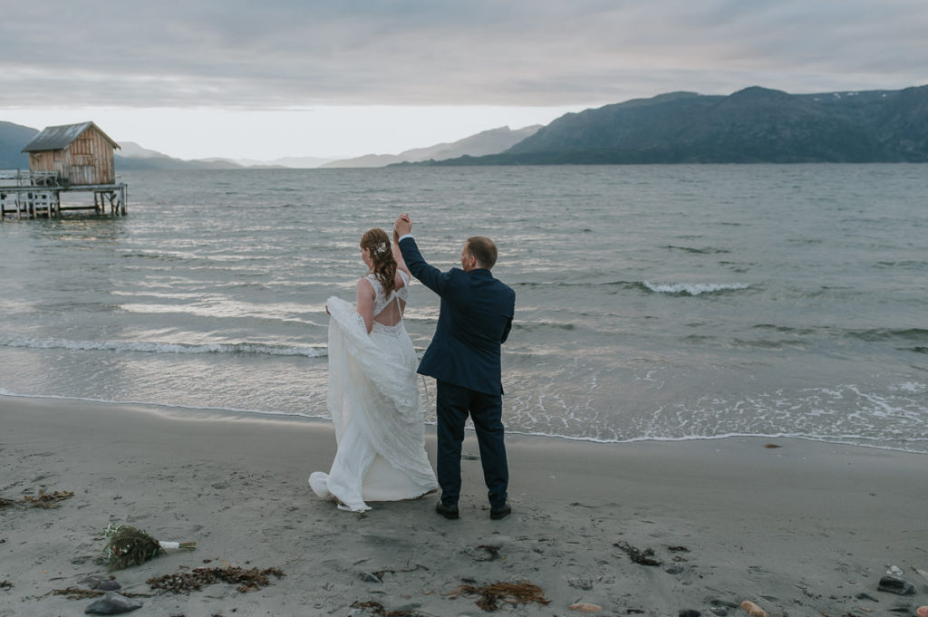 Bride and groom dancing on a beach with a sunset and mountain view in Storekorsnes Alta Norway 