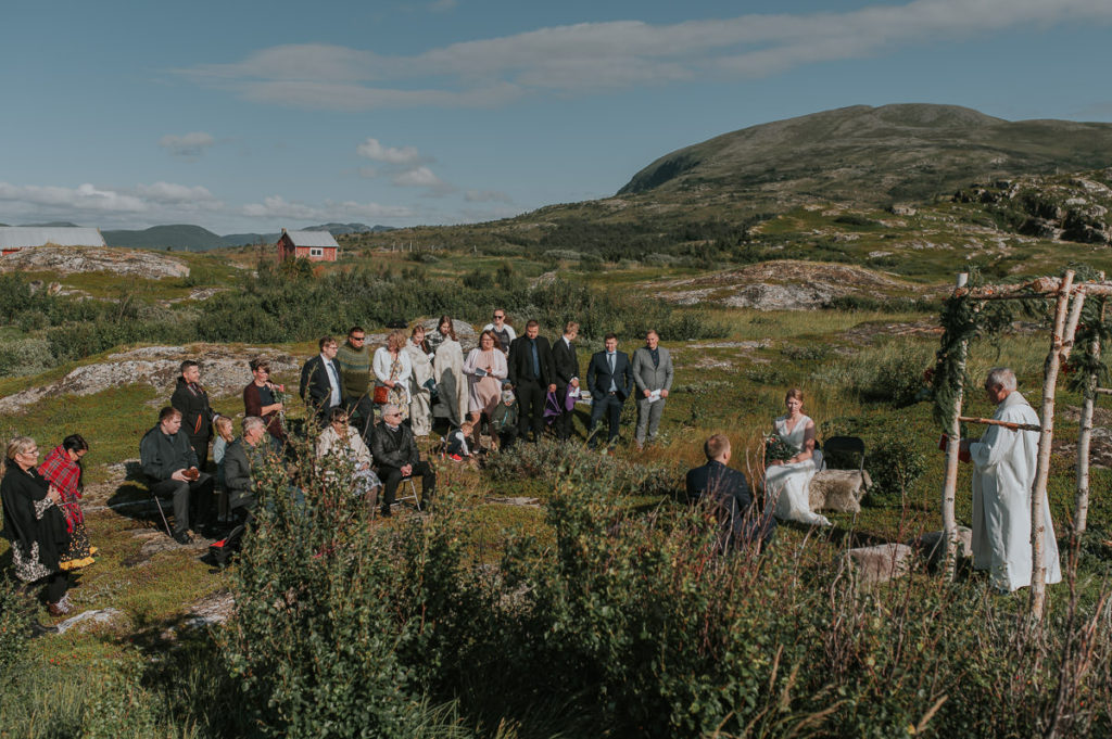 Intimate outdoor wedding ceremony under a floral arch  in Storekorsnes near Alta Norway by the fjords with a sea view and mountains