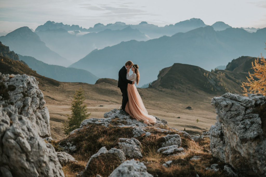 Bride and groom in a field with a stunning mountain view in Northern Italy - by dolomites elopement wedding photographer TS Foto Design