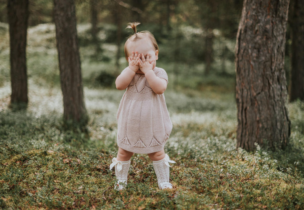 En jente på ett år leker borte-bø utendørs på sin ettårsdag
