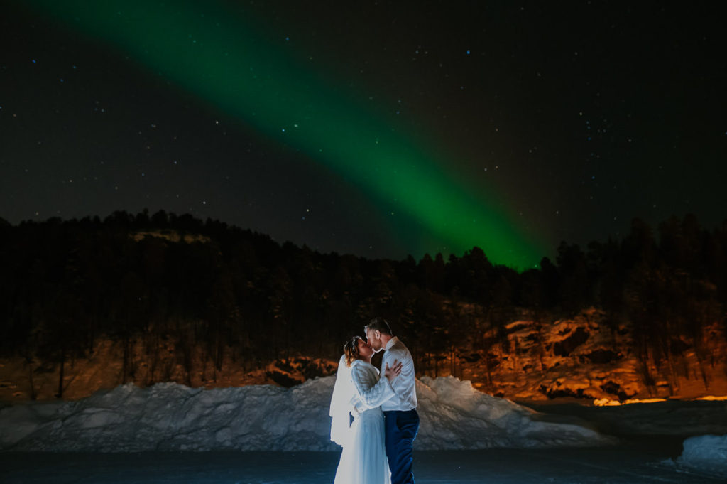 Bride and groom kissing under the Northern lights aurora borealis in Alta Norway on the day of their winter wedding