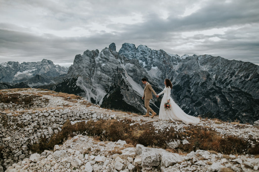 Bride and groom holding hands and hiking in the Italian Dolomites on the day of their intimate wedding