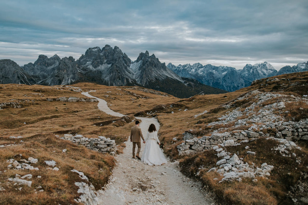 Bride and groom walking on a muntain trail in Italian Dolomites on the day of their adventure wedding - by europe elopement photographer TS Foto Design