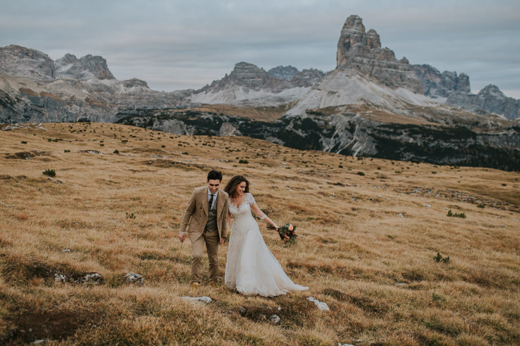Bride and groom walking on a muntain trail in Italian Dolomites on the day of their adventure hiking elopement