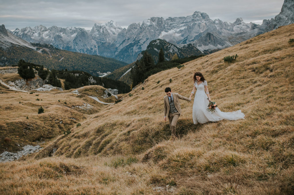 Bride and groom walking on a muntain trail in Italian Dolomites on the day of their adventure hiking elopement wedding