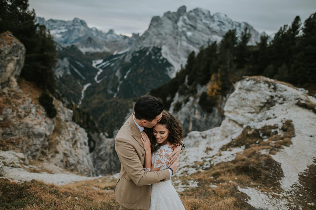 Beautiful couple in wedding attire kissing among stunning nature of Northern Italy