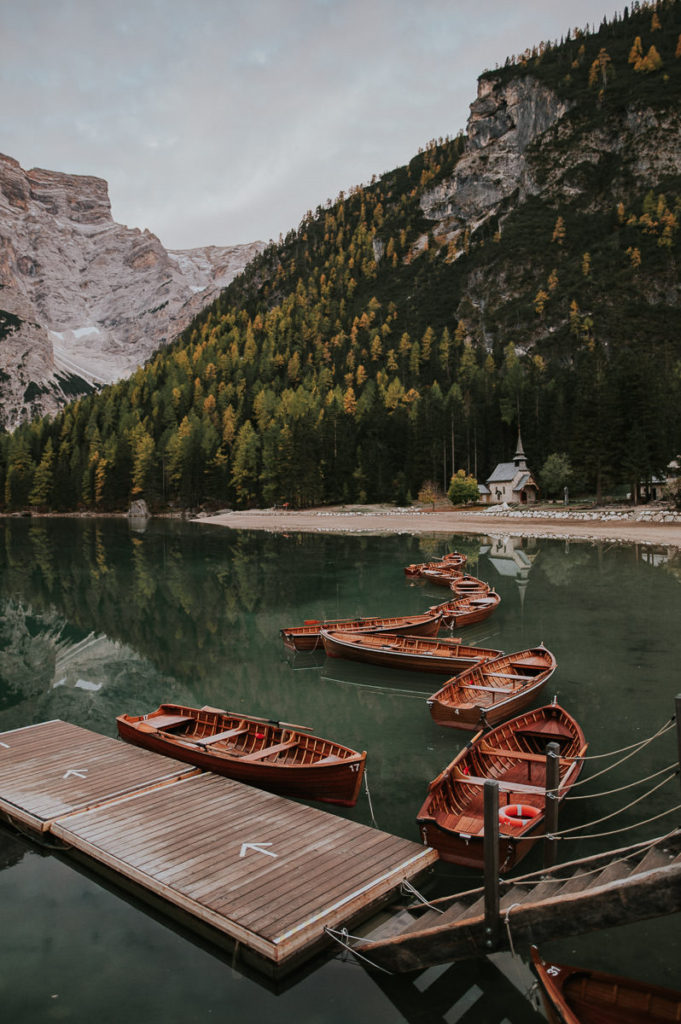 Beautiful emerald green mountain lake in Italy with wooden rowing boats