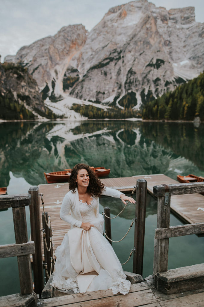 Stunning bride walking by the Lake Braies in Italy on her wedding day