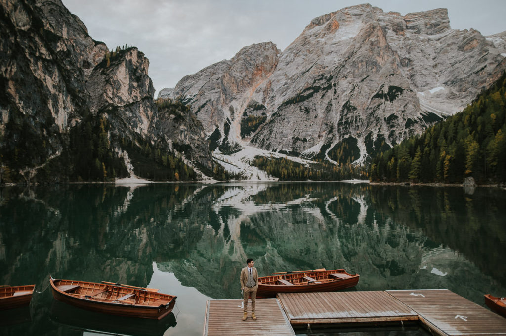Groom waiting for his bride on the quay at Lago di Braies in Italian Dolomites