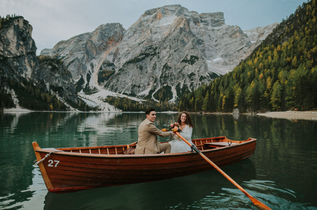 Bride and groom rowing a boat on a mountain lake Lago di Braies Pragser wildsee on the day of their Dolomites elopement