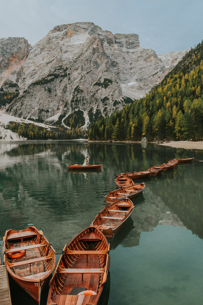 Bride and groom rowing a boat on a mountain lake Lago di Braies Pragser wildsee on the day of their Dolomites elopement captured by elopement wedding photographer TS Foto Design
