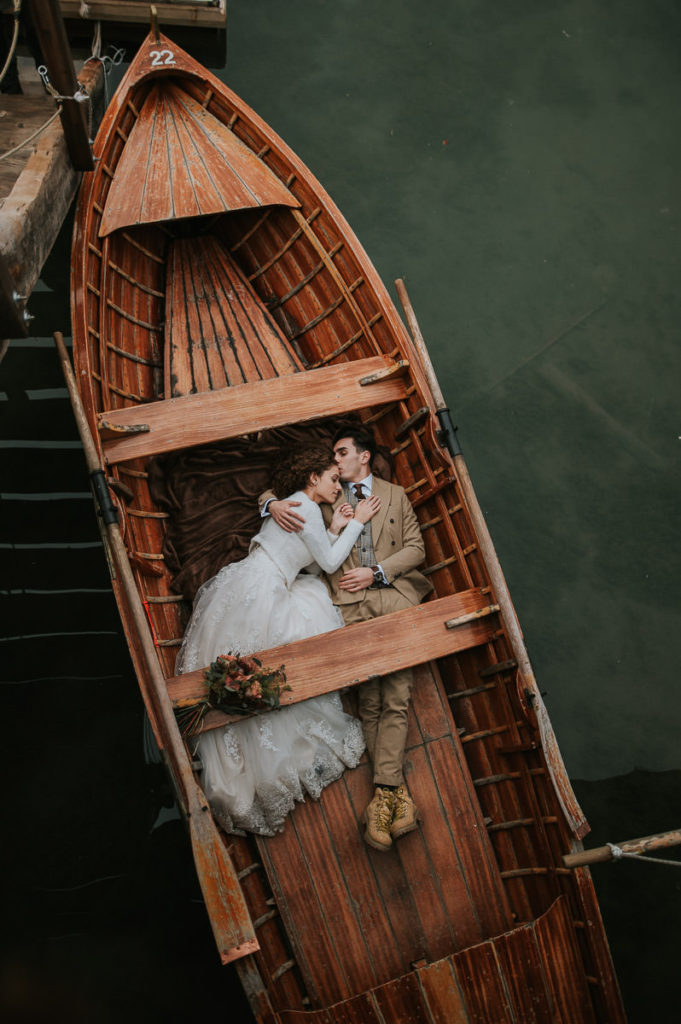 Bride and groom laying in a wooden boat and kissing on Lago di Braies on the day of their elopement in Italy