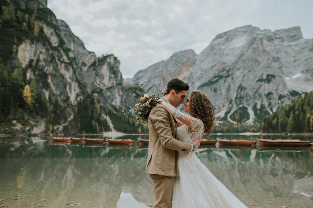Bride and groom walking on a beach at Lake Braies Pragser wildsee Lago di braies on their elopement wedding day