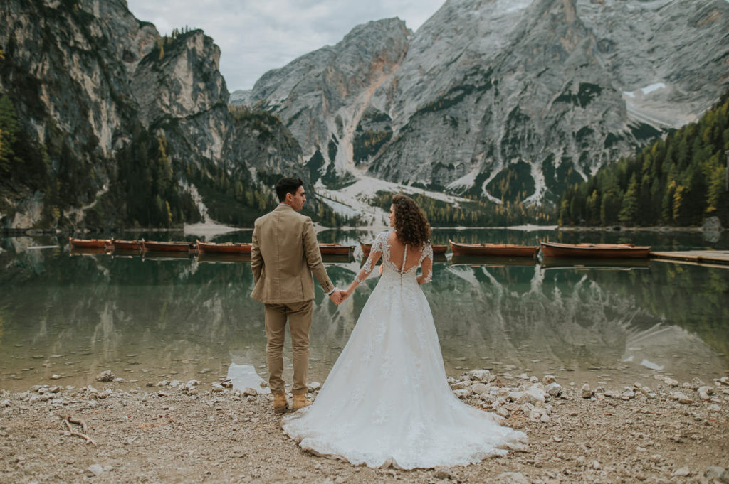 Bride and groom walking on a beach at Lake Braies Lago di braies on their elopement day by wedding photographer TS Foto Design