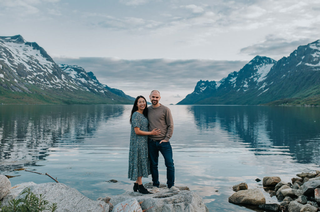 A beautiful couple walking by the fjord Ersfjord in Tromsø on the day of their engagement photo session - by wedding photographer TS Foto Design