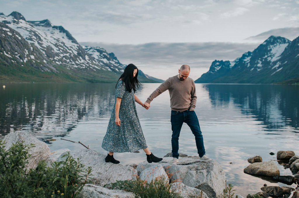 A beautiful couple walking by the fjord Ersfjord in Tromsø on the day of their engagement photo session - by wedding photographer TS Foto Design