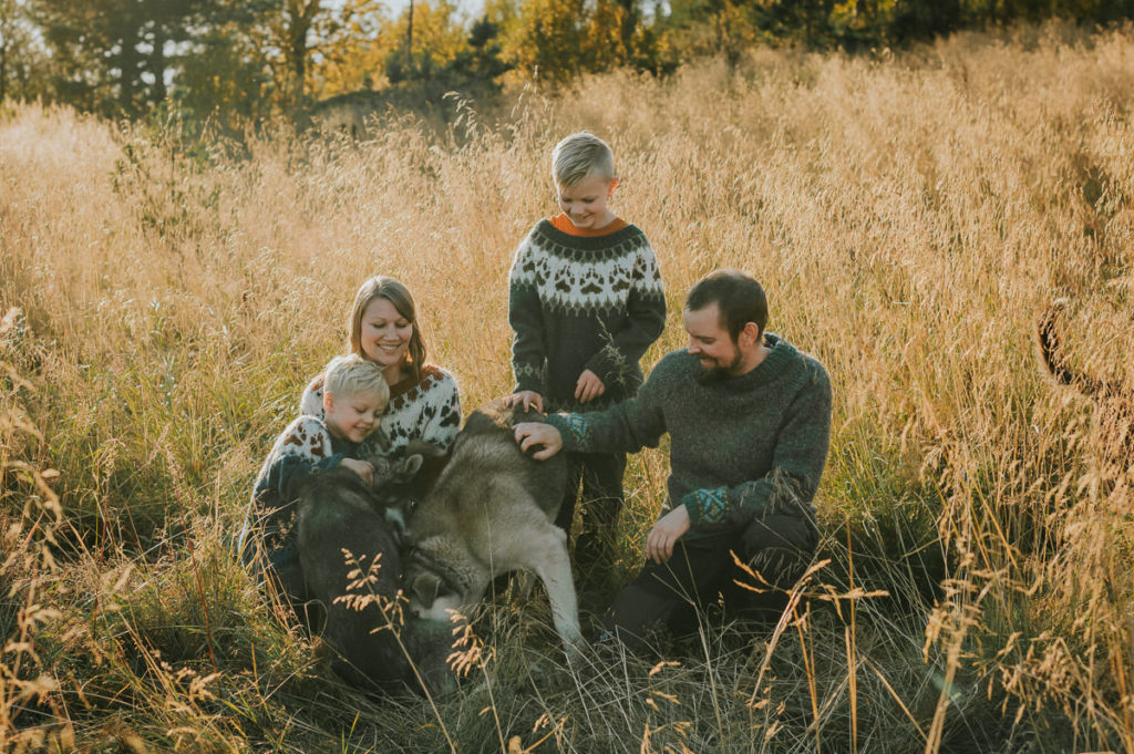 En familie samler sine husky hunder for en familiefotografering sammen med dem