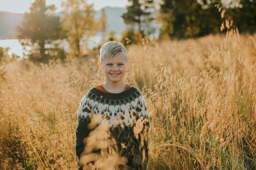 Skjønn gutt på en barnefotografering ute i naturen blant nydelige høstfarger