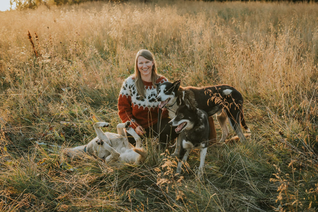 Portrettfoto av en ung dame som spaserer ute i villmarka sammen med sine husky hunder utenfor Alta i Finnmark fotografert av familiefotograf TS Foto Design