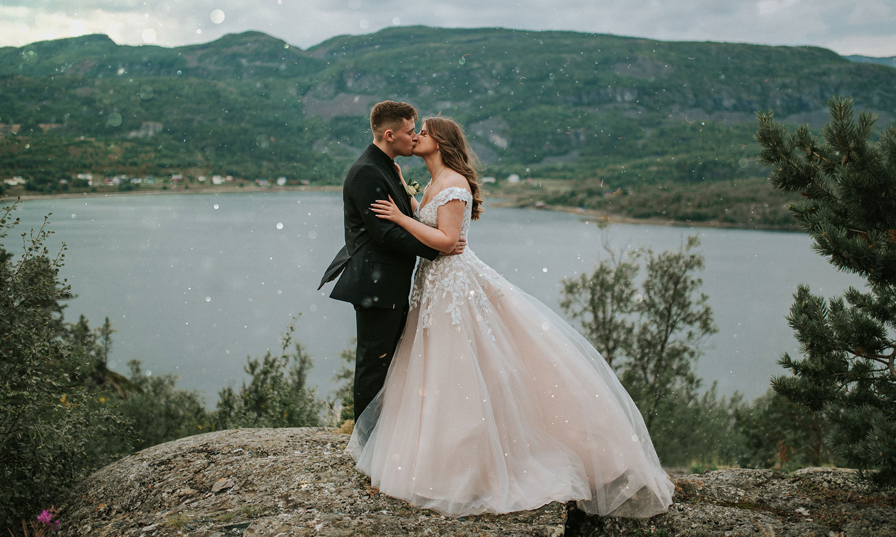 Nydelig brudepar kysser foran et flott utsikt til fjord og fjell i Alta Norge