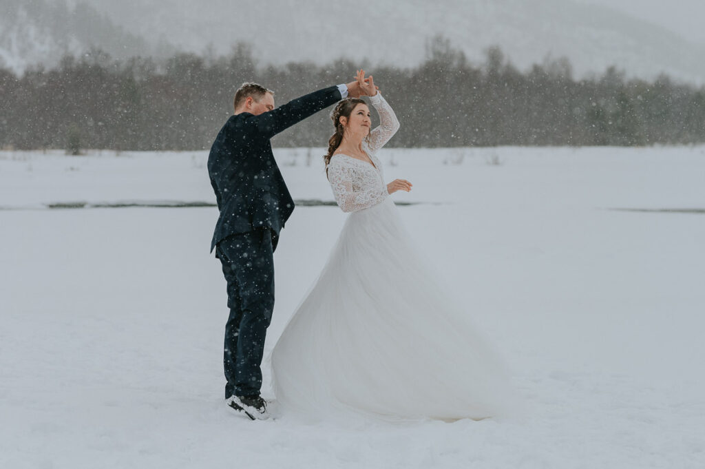 Bride and groom dancing in front of   winter landcape in Alta Northern Norway under a beautiful blizzard snowfall right before their dogsledding winter wedding ceremony in Norway