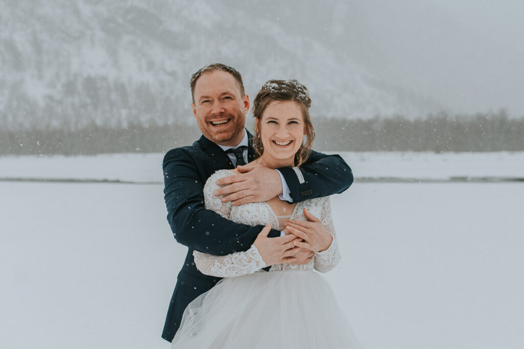 Bride and groom walking into a  white winter landscape in Alta Northern Norway under a beautiful blizzard snowfall right before their dogsledding winter wedding ceremony in Norway