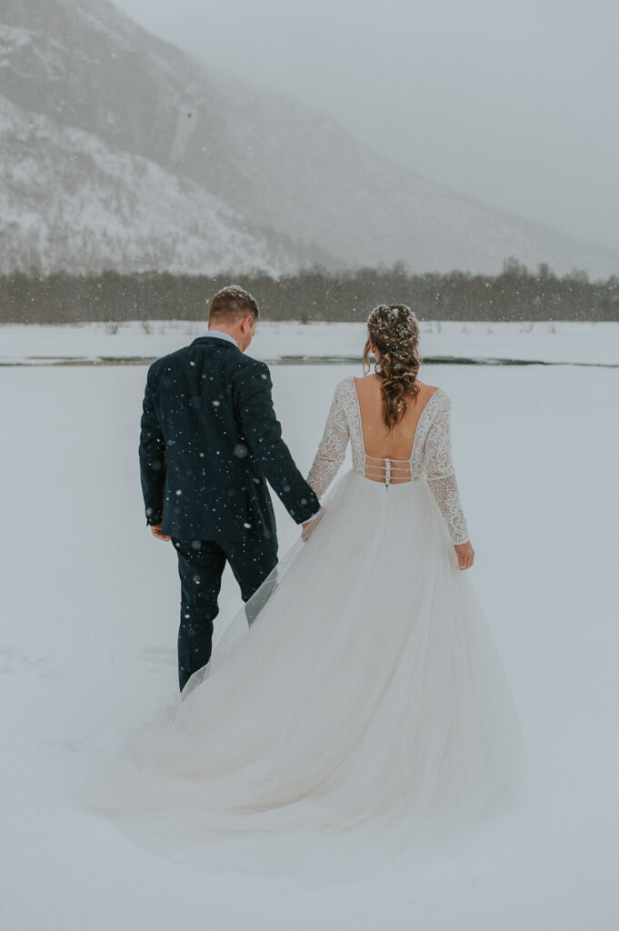 Bride and groom portraits in front of   winter landcape in Alta Northern Norway under a beautiful blizzard snowfall right before their dogsledding winter wedding ceremony in Norway