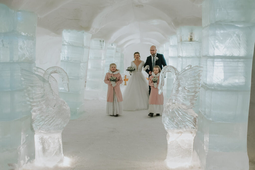 Bride is walking down the isle in the igloo hotel Sorrisniva in Alta Norway on her winter wedding day