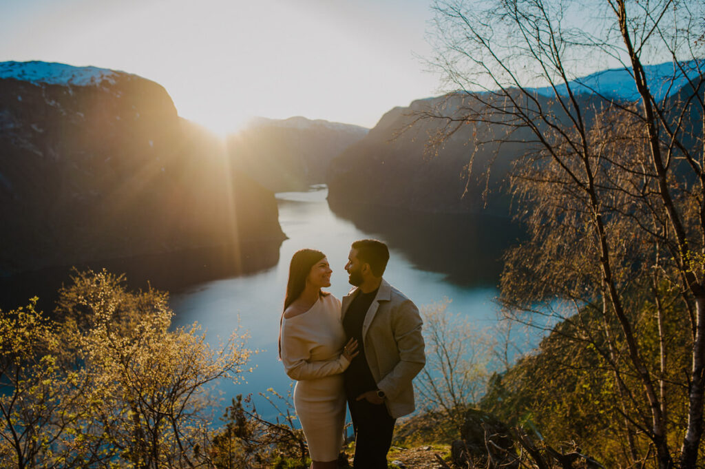 Beautiful couple watching sunset by the fjord in Aurland Norway on the day of their engagement