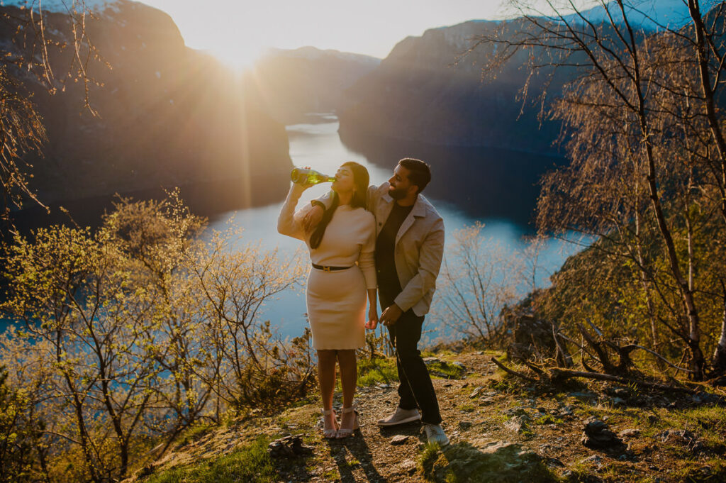 Beautiful couple popped up sparkling wine by the Aurlandsfjord in the sunset  to celebrate their engagement