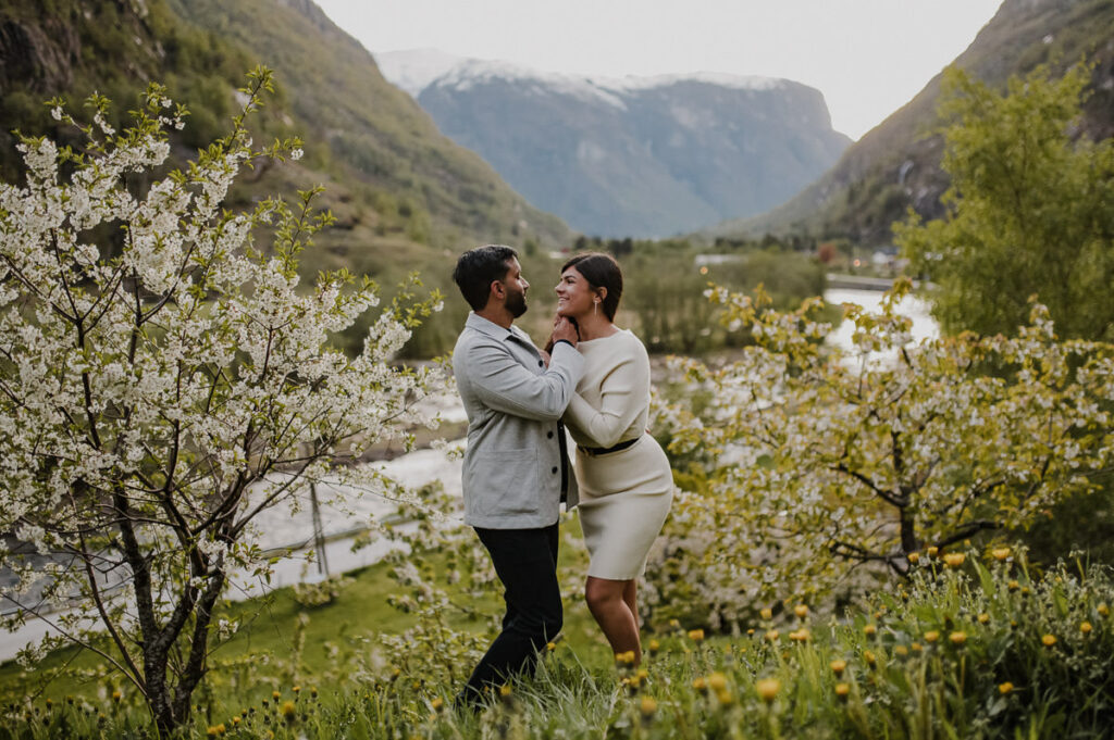 Beautiful couple among blooming apple trees in Aurland Western Norway on the day of their engagement photo session