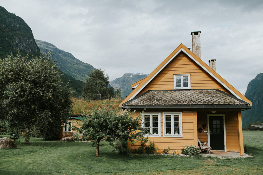 Cozy yellow airbnb cabin in front of mountains and trees in Western Norway