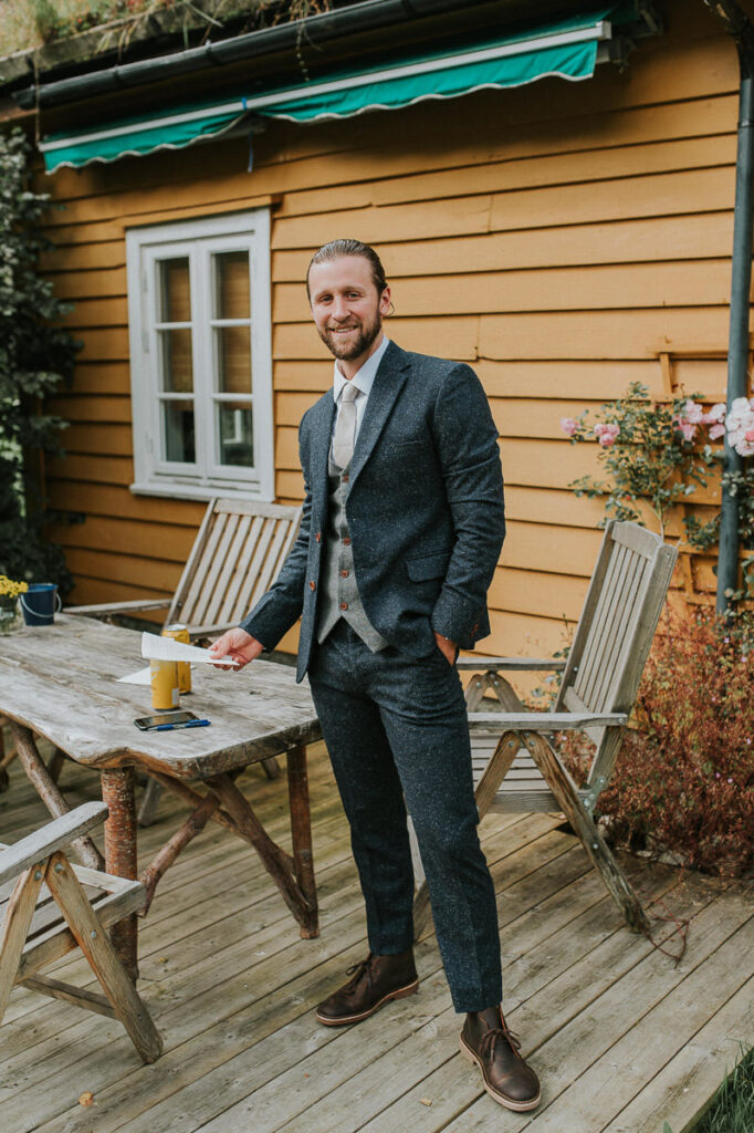 Groom is waiting for his bride outside of yellow cabin in Loen Western Norway
