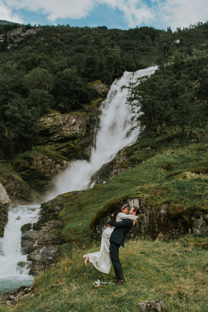 Bride and groom kissing in front of a stunning waterfall in Loen, Norway