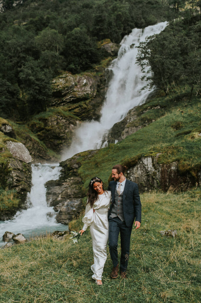 Bride and groom walking by the stunning waterfall in Loen, Norway on the day of their elopement