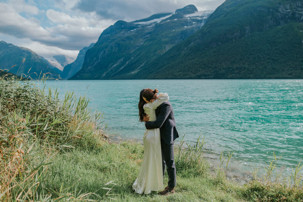 Bride and groom hugging in front of a beautiful glacier lake in Loen, Western Norway