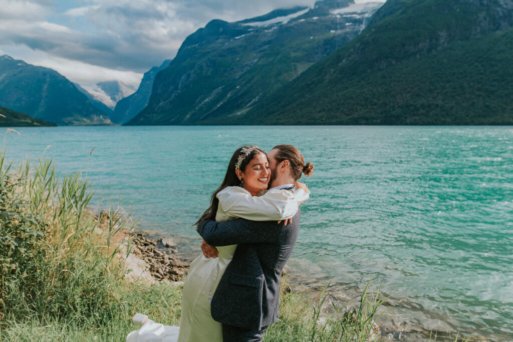 Bride and groom hugging in front of a beautiful turquoise blue-green glacier lake in Loen, Western Norway