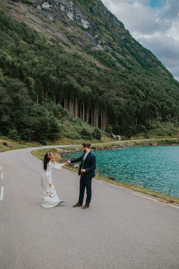 Bride and groom dancing in the middle of the road next to a blue lake in Loen, Western Norway