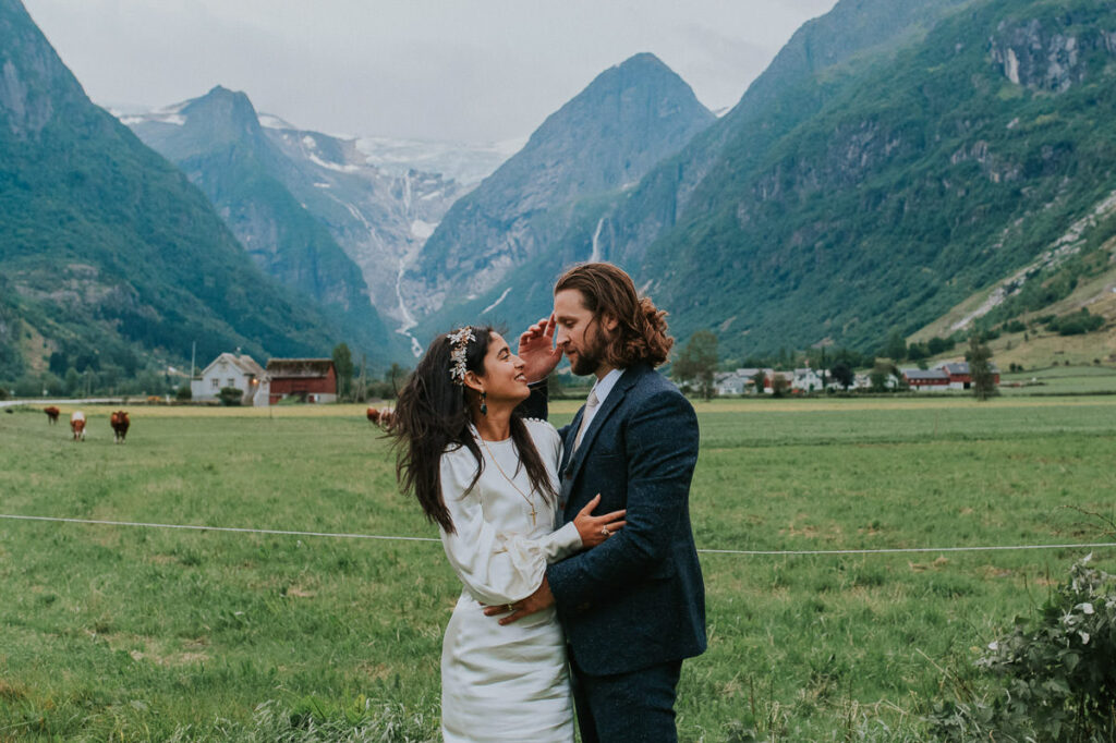 Bride and groom in front of a beautiful picturesque view to the mountains, glacier and cows in Loen Stryn on the day of their elopement