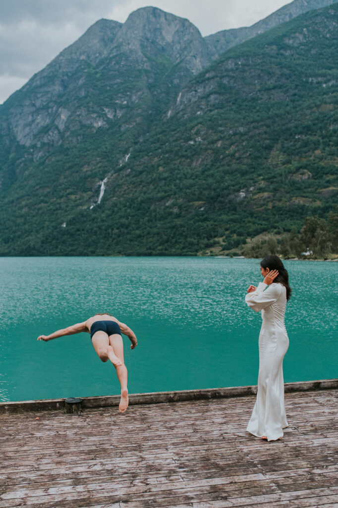 A groom in his underwear is jumping in a beautiful glacier lake in Loen while bride is watching him, happening on the day of their elopement after the ceremony and other adventures